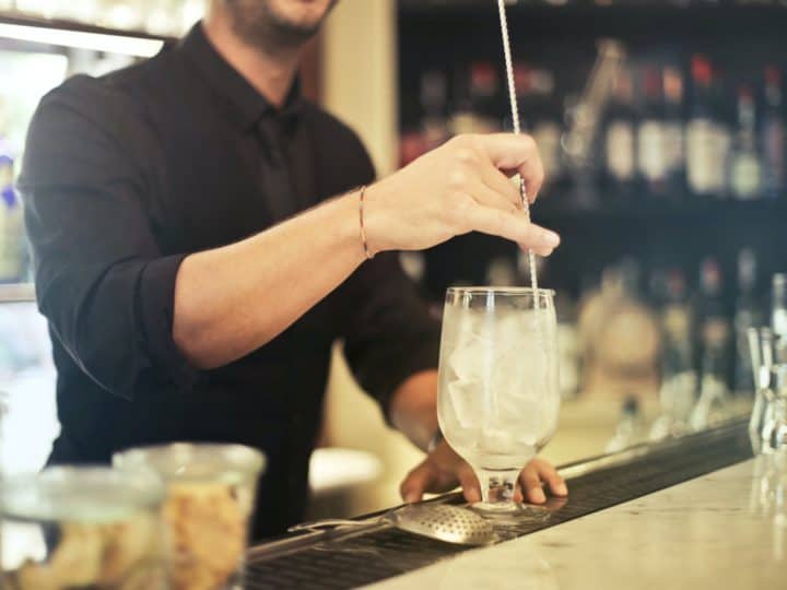 crop barman making cocktail in pub