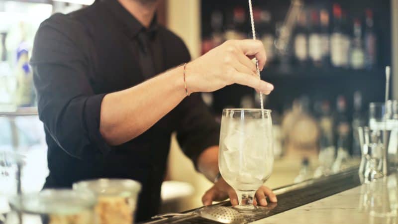 crop barman making cocktail in pub